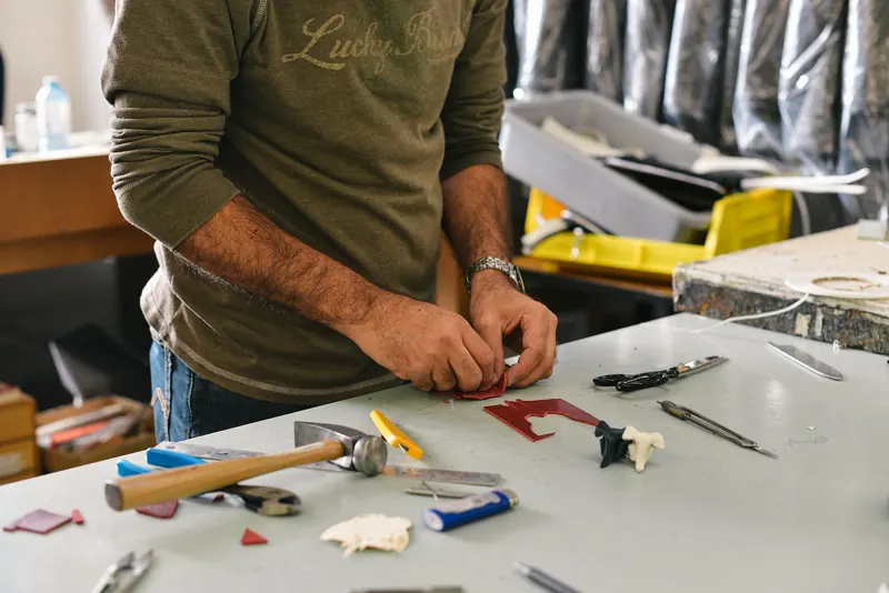 Kursleiter arbeitet mit Werkzeug an einem Werktisch